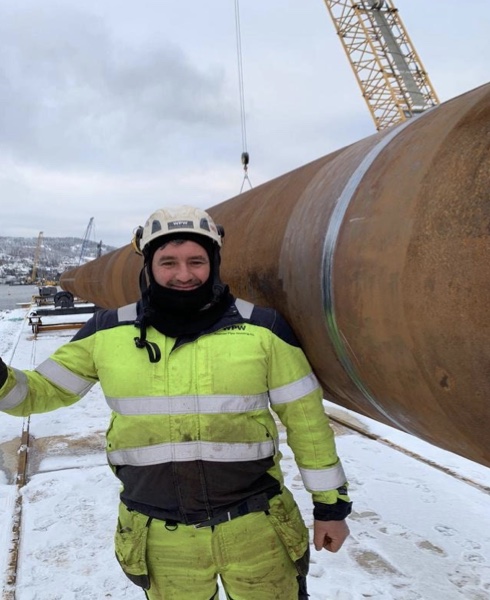 Technical worker beside a large industrial pipe section